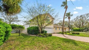 A residential house with a garage, surrounded by a well-maintained lawn and palm trees. - Sunshine Hideaway - Team Joseph Ellen (Jacksonville Beach)