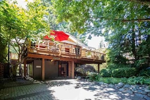 A wooden building with a balcony, surrounded by trees and greenery.