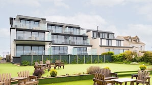 A modern multi-story residential building with balconies, a well-maintained lawn, and outdoor seating. - 8 Beachview -  apartment in Crantock sleeps 4 guests in 1 bedroom (Crantock)