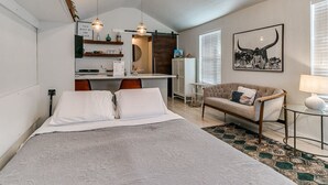 A bedroom with a large bed, a desk, a sofa, and a dining area.
