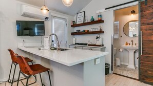 A modern kitchen with a central island, bar stools, a built-in oven, and a large window.