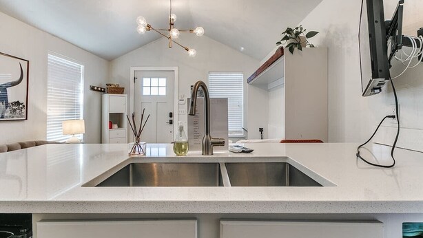 A modern kitchen with a large island, stainless steel appliances, and pendant lighting.