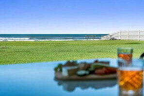 A beach view with a table, a bench, and a fence.