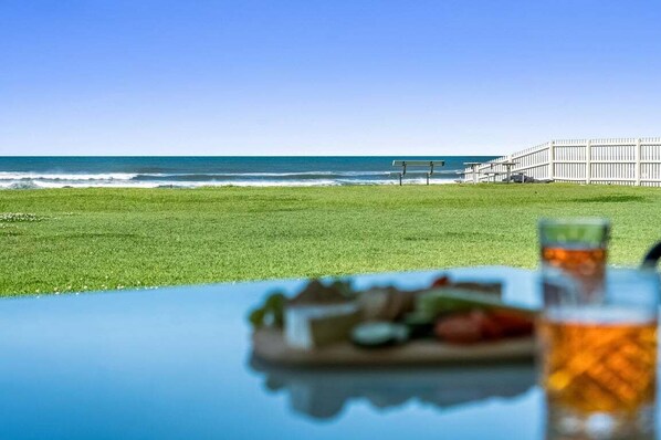 A beach view with a table, a bench, and a fence.