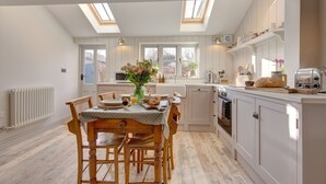 A modern kitchen with a dining area, featuring skylights, wooden flooring, and white cabinetry. - The Flints - sleeps 3 guests  in 2 bedrooms (Langham)