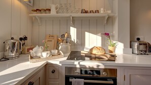 A modern kitchen with white cabinetry, a built-in oven, a toaster, and various kitchen appliances. - The Flints - sleeps 3 guests  in 2 bedrooms (Langham)