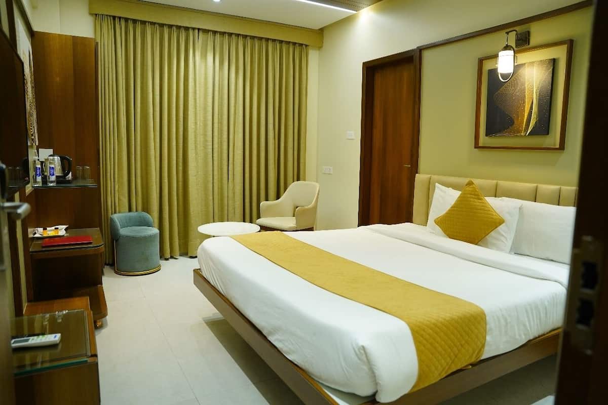A hotel room with a large bed, a bedside table, a chair, a desk, and a wardrobe.
