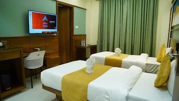 A hotel room with two beds, a desk, a chair, a television, and a green curtain.