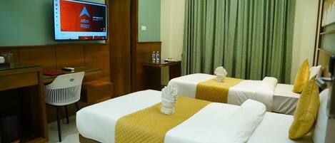 A hotel room with two beds, a desk, a chair, a television, and a green curtain.