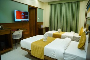 A hotel room with two beds, a desk, a chair, a television, and a green curtain. - Hotel Riddhi Executive (Latur)