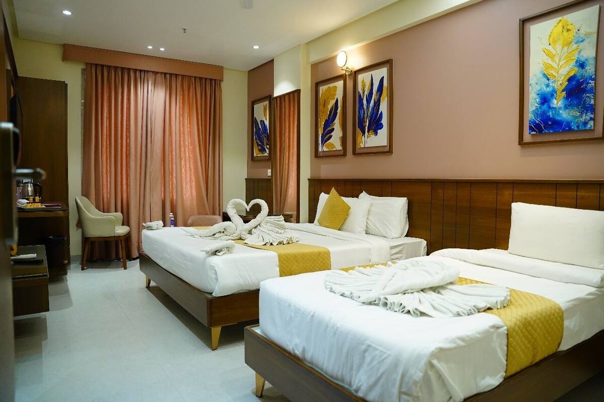 A hotel room with two beds, a desk, a chair, and artwork on the walls.