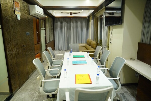 A conference room with a long table, chairs, a sofa, and a TV.