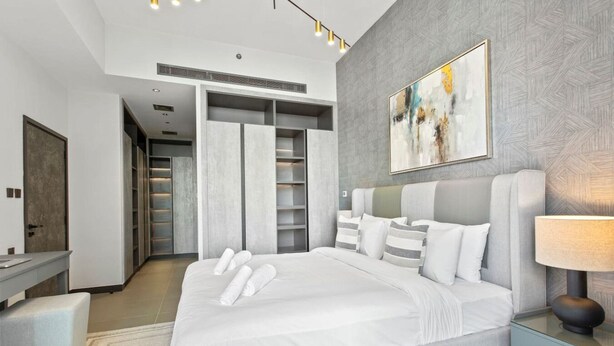 Een moderne slaapkamer met een groot bed, een inloopkast en een schilderij aan de muur.