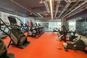 Un gimnasio con cintas de correr, bicicletas estáticas y máquinas de pesas.