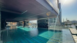 Een dakzwembad met oneindige rand, helderblauw water, omgeven door moderne architectuur en uitzicht op een moskee.