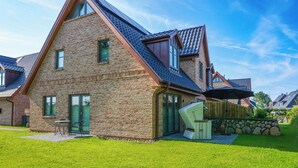 A modern brick house with a sloped roof, a stone wall, and a well-maintained lawn. - "Vacation in vacation home Levi: relaxation and adventure on Sylt!" (Sylt / OT Tinnum)