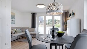 A modern living room with a dining table, sofa, and a large window. - "Vacation in vacation home Levi: relaxation and adventure on Sylt!" (Sylt / OT Tinnum)