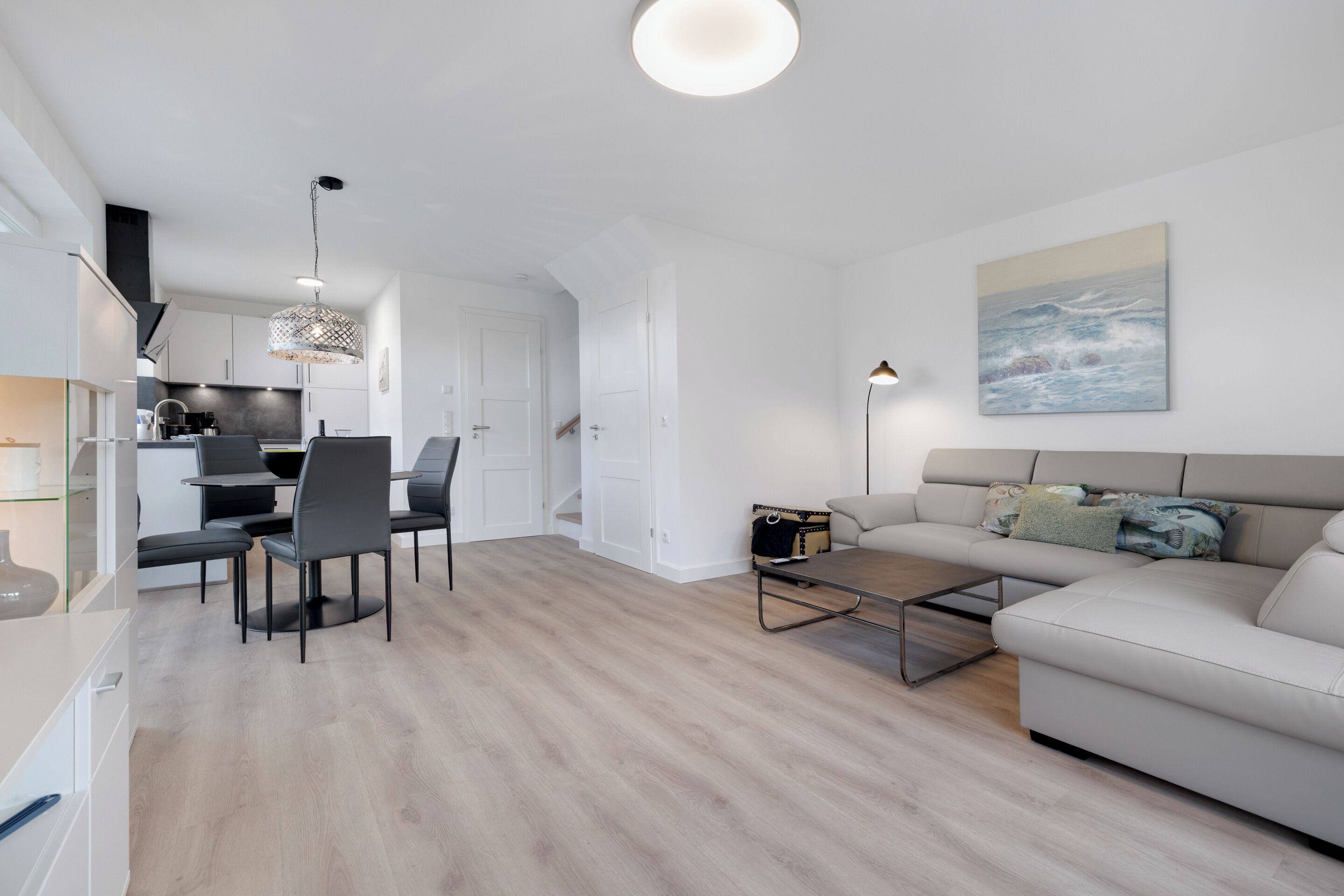 Un salon moderne comprenant un canapé, une table basse et un coin repas avec des chaises.