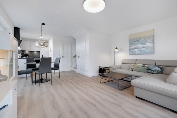 Un salon moderne comprenant un canapé, une table basse et un coin repas avec des chaises.