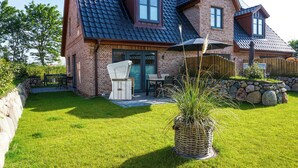 A brick house with a dark tiled roof, a patio with outdoor furniture, and a stone wall. - "Your perfect vacation paradise on Sylt - the vacation home Lena awaits you!" (Sylt / OT Tinnum)