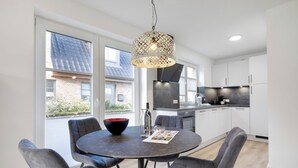 A modern kitchen with white cabinets, a black countertop, and a hanging pendant light. - "Your perfect vacation paradise on Sylt - the vacation home Lena awaits you!" (Sylt / OT Tinnum)