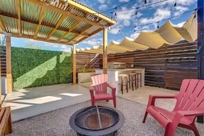 Eine Terrass mit Pergola, Sitzgelegenheiten und einem Feuerkorb.