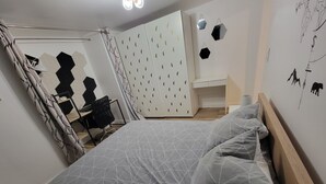 Et soveværelse med seng, skrivebord og garderobeskab.