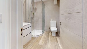 Une salle de bain moderne avec une douche à parois de verre, des toilettes et un meuble-lavabo avec des tiroirs.