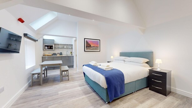 Une chambre d’hôtel moderne équipée d’un lit, d’une table de chevet et d’un petit bureau.