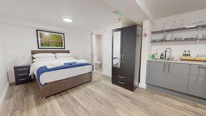 Ett modernt hotellrum med en säng, en garderob, ett badrum och ett litet kök.