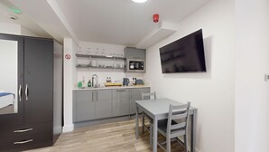 Ett kompakt kök med mikrovågsugn, diskho och en matplats med bord och stolar.