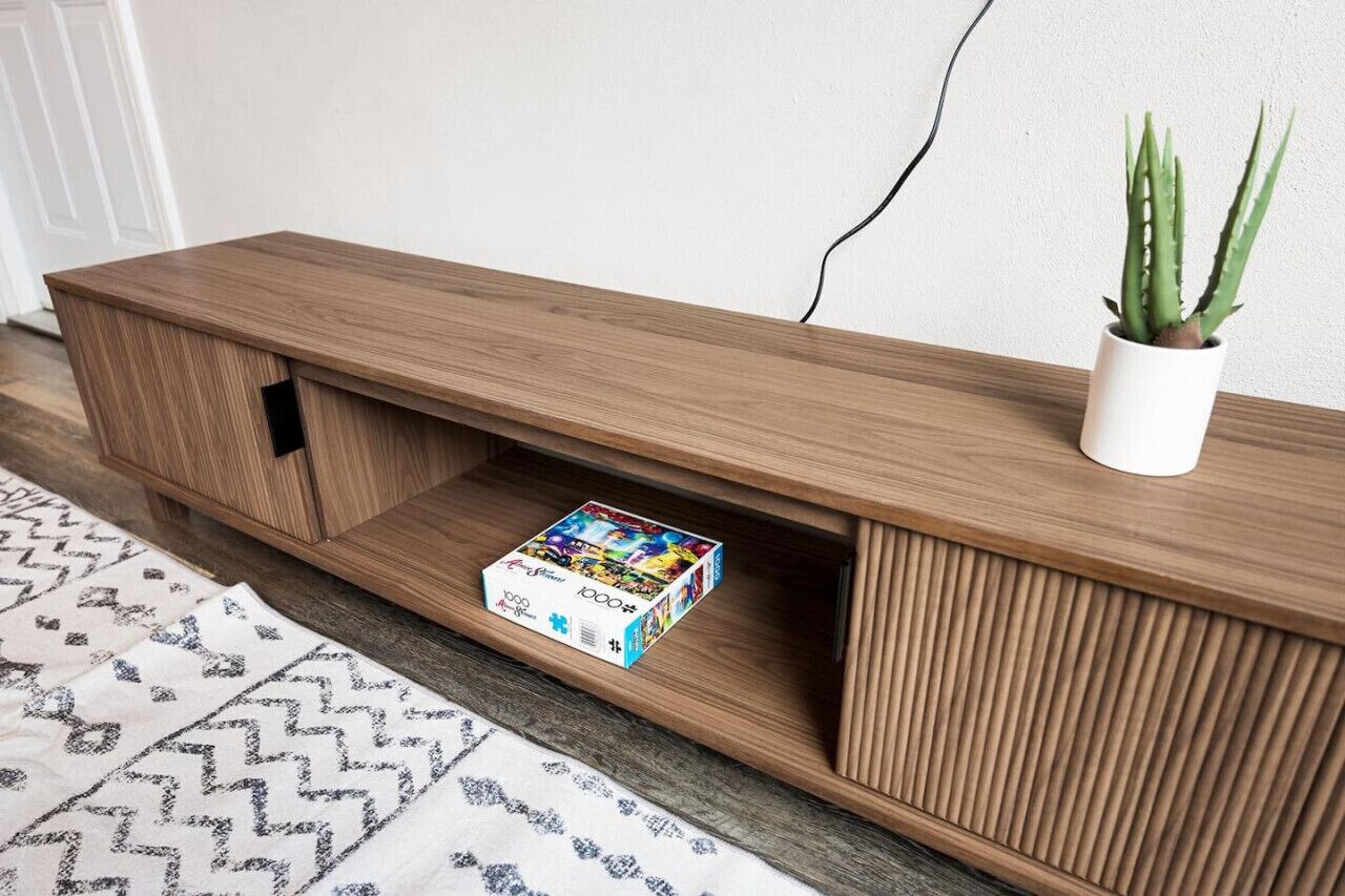 Una consola de madera con una planta de aloe vera en la parte superior.