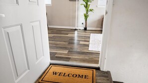 A hallway with a welcome mat, wooden flooring, a potted plant, and a door. - A Trendy Escape close to Downtown Peoria (Peoria)