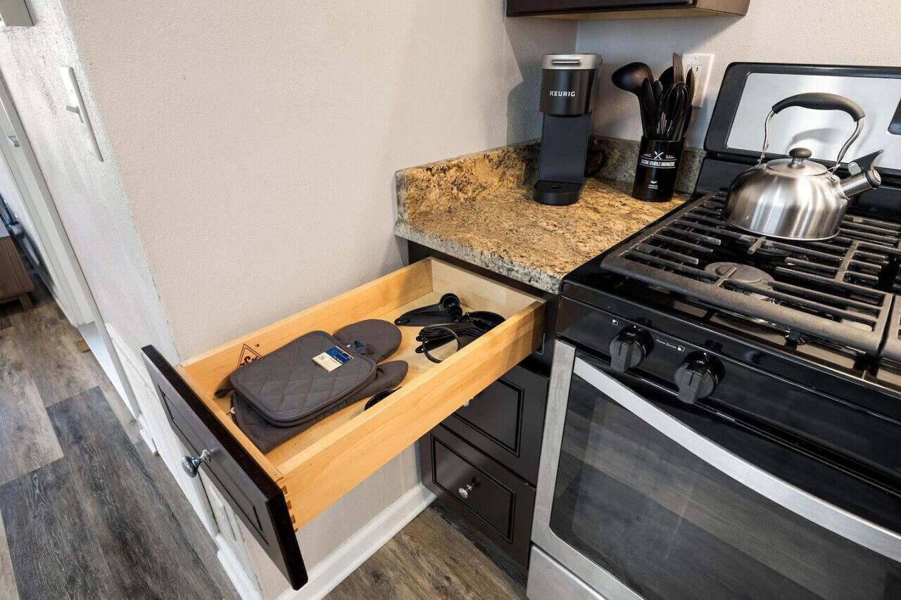 A kitchen with a built-in stove, a coffee maker, and a kettle on the countertop.