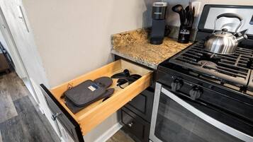 A kitchen with a built-in stove, a coffee maker, and a kettle on the countertop.