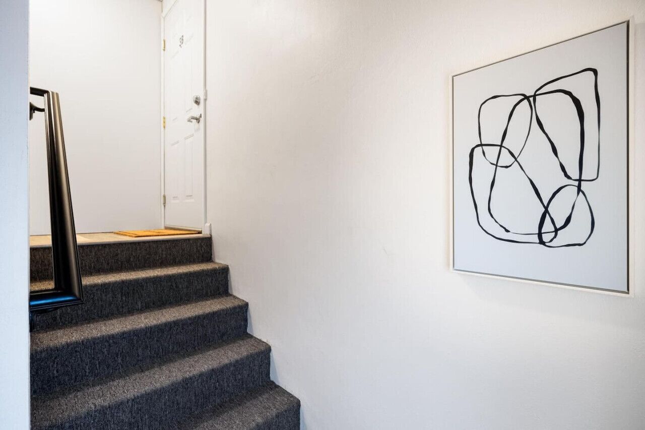 Una escalera con una obra de arte abstracta enmarcada en la pared.