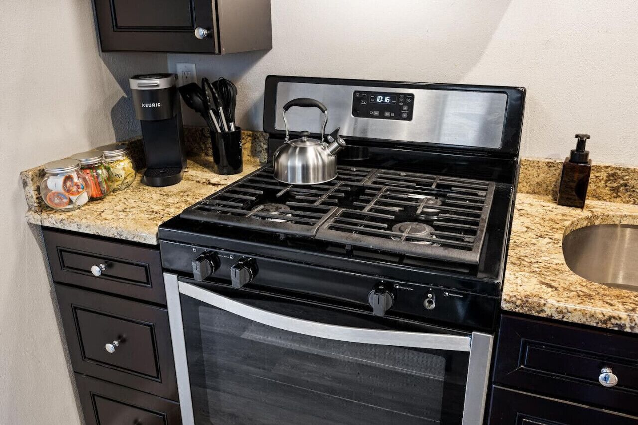 Una cocina con estufa de acero inoxidable, horno y encimera de granito.