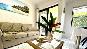 A living room with a sofa, coffee table, and a potted plant.
