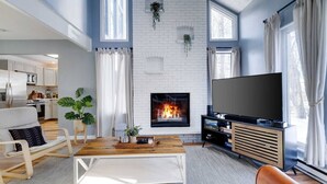 A modern living room with a fireplace, a television, and a dining area. - Pocono Lake Charmer: Lakeview Retreat for 10 (Tobyhanna)