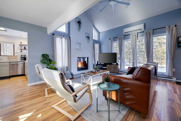 A modern living room with a fireplace, a sofa, a TV, and a dining area.