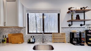 A modern kitchen with a stainless steel sink, wooden cutting board, and a coffee machine. - Pocono Lake Charmer: Lakeview Retreat for 10 (Tobyhanna)