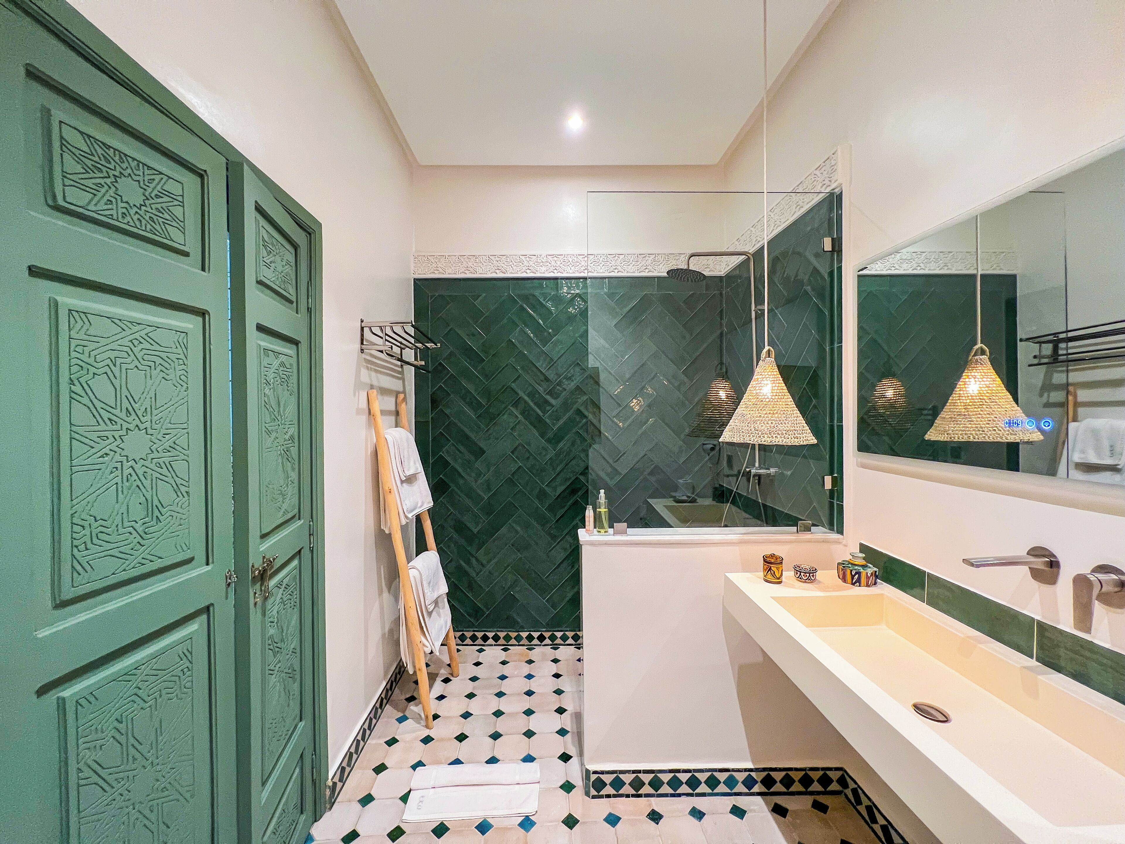 A bathroom with a green door, a white sink, a mirror, and patterned floor tiles.