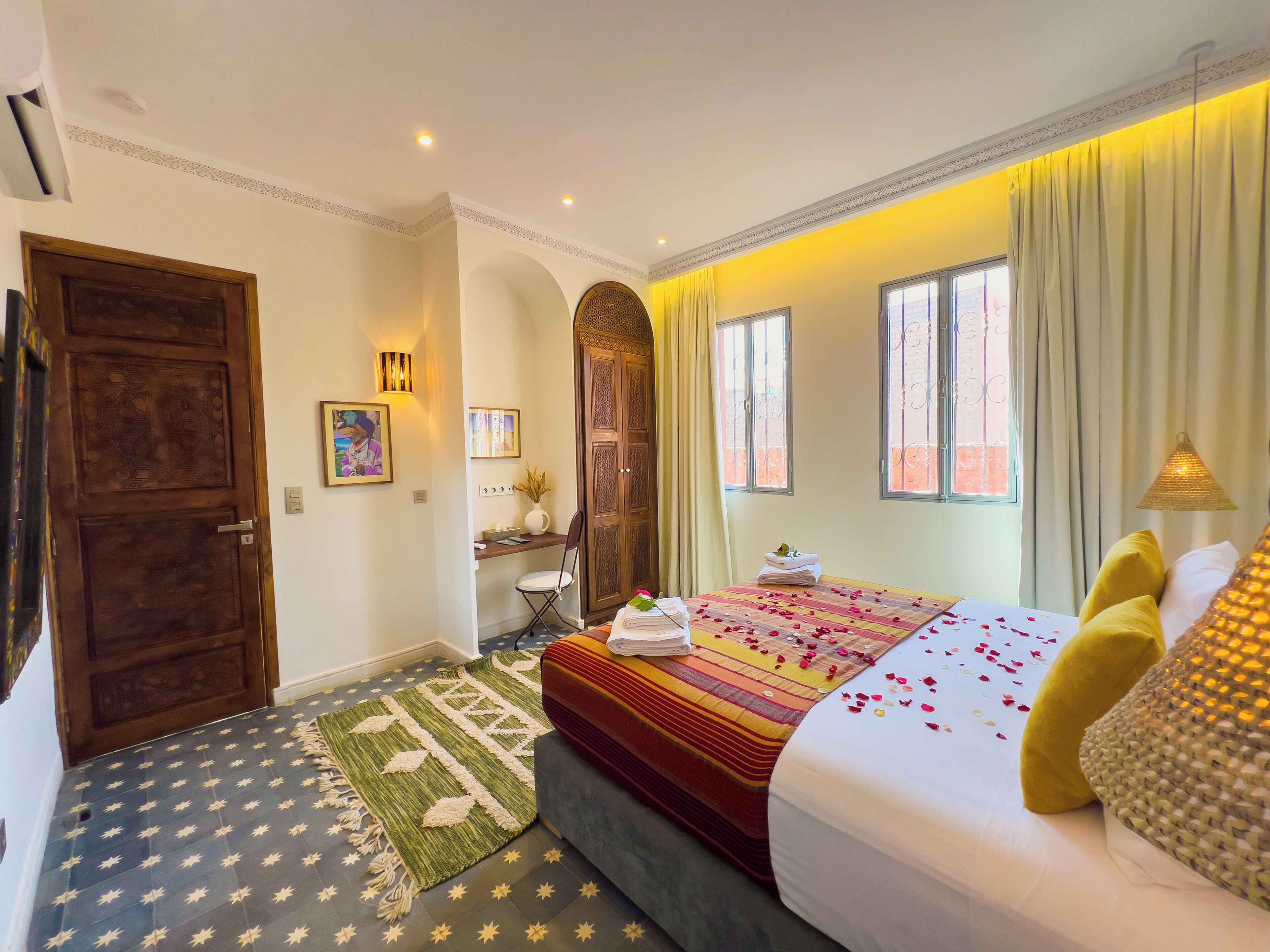 A hotel room with a bed, a desk, a chair, and a door.