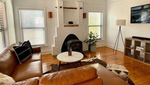 A living room with a fireplace, leather sofas, a coffee table, and a television on a stand.