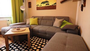 A living room with a grey sofa, a small wooden table, and a polka dot rug. - Ferienwohnung Sommergluck in Proseken (Gaegelow)