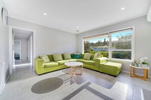 A modern living room with a green sofa set, a round coffee table, and a large window with a view.