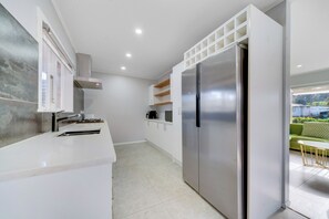 A modern kitchen with white cabinetry, a stainless steel refrigerator, and a built-in oven.
