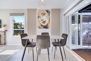 A dining area with a table, chairs, and a large painting on the wall.
