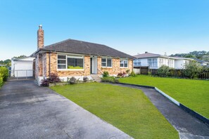 A two-story house with a brick facade, a chimney, and a well-maintained lawn.