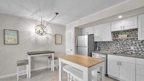 Una cocina moderna con armarios blancos, un refrigerador de acero inoxidable y un salpicadero de baldosas blanco y negro.